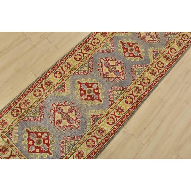A tribal Caucasian Kazak runner hand-knotted with fine wool on a cotton foundation. This rug features a row of geometric...