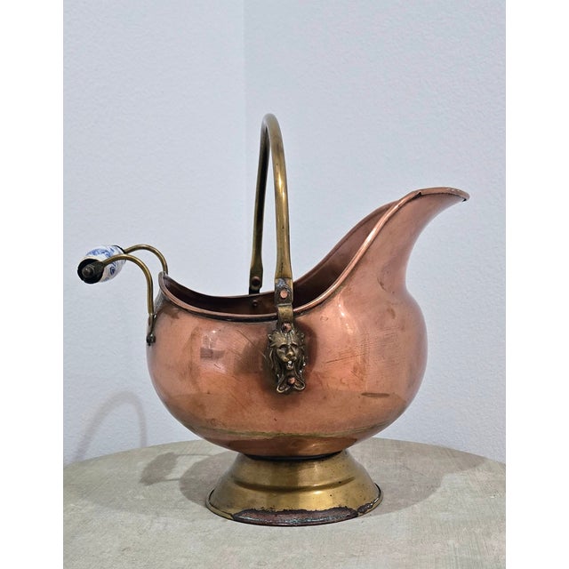 Charming vintage Dutch coal scuttle crafted in warm copper with a contrasting brass foot and swing handle, accented by...