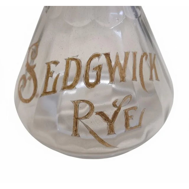 Elegant hand-painted glass whiskey decanter advertising Sedgwick Rye, dating to the late 19th century. This example was...