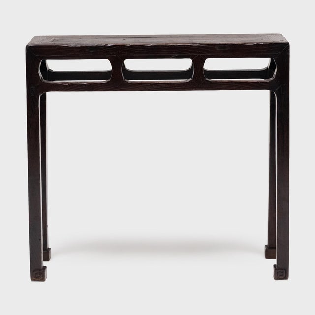 This narrow console table from the late 19th century balances streamlined form with the rich textures of antique...