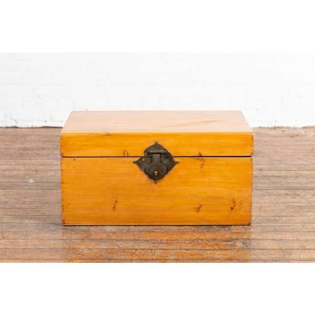 A Chinese elmwood blanket chest from the early 20th century, with lateral handles. Created in China during the early years...