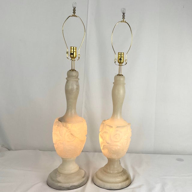 An elegant and timeless pair of table lamps crafted from beautifully carved alabaster, showcasing delicate floral relied...