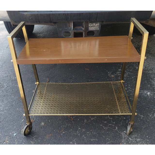 A Mid-Century Brass and Formica top Rolling Cart. Measures 25" in width, 13.5" in depth and stands 25" tall. Lower tier is...