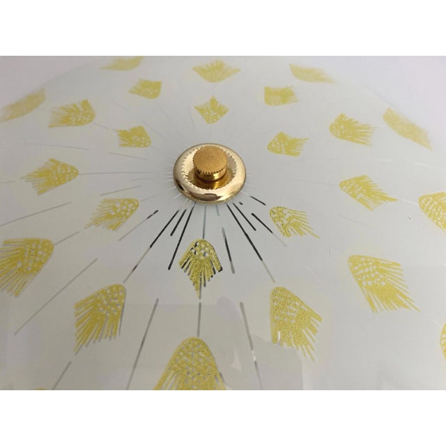Radiant sunburst flush mount ceiling light featuring a frosted glass shade with gold beaded underside, transparent rays...