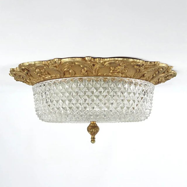 Classic heavily detailed flush mount made of brass and glass. The fixture is casted in a French lily motif and the heavy...
