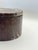 A substantial round keepsake box crafted from richly veined Red Zebra marble, featuring deep burgundy, rust and cream...