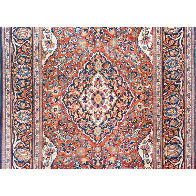 A playful early 20th century Persian Kashan rug with a wonderful central floral medallion woven in crimson, indigo, coral,...