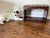 A charming Art Deco vanity bench featuring a warm brown wood finish, gracefully shaped apron, and newly upholstered seat...