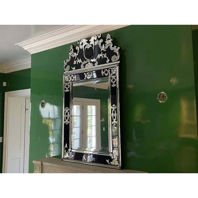 A tall French Venetian-style wall mirror with a rectangular central plate framed by bluish-black glass panels overlaid...