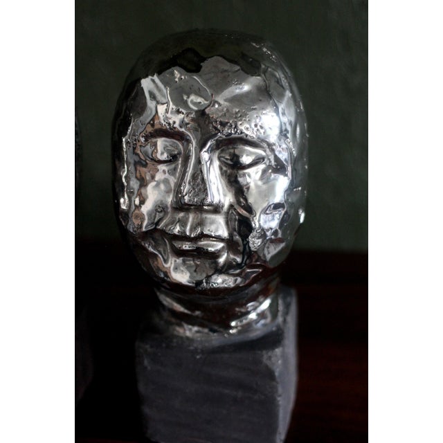 A set of 3 sculptural heads in a Brutalist or simplified style. Pottery with a shiny silver and matte black glaze. Very...