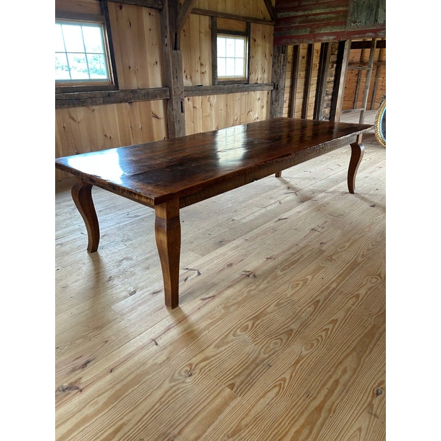 Impressive in scale and full of hand hewn character, a gigantic reclaimed barn wood farm table having cabriole legs and...