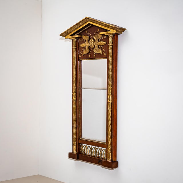 Wall mirror with a mahogany-veneered frame and giltwood elements, featuring a pediment top and flanking half-columns with...