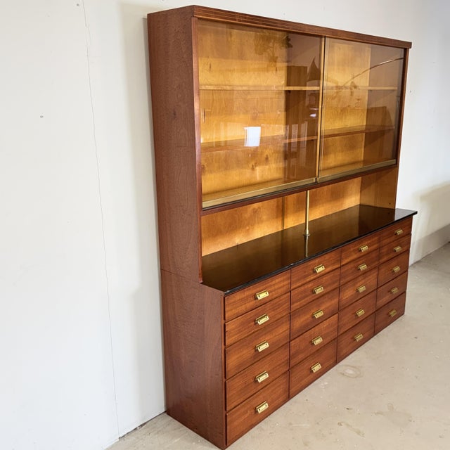 Stunning and highly functional apothecary cabinet from post-war Germany (circa 1950-1960), crafted in warm mahogany veneer...