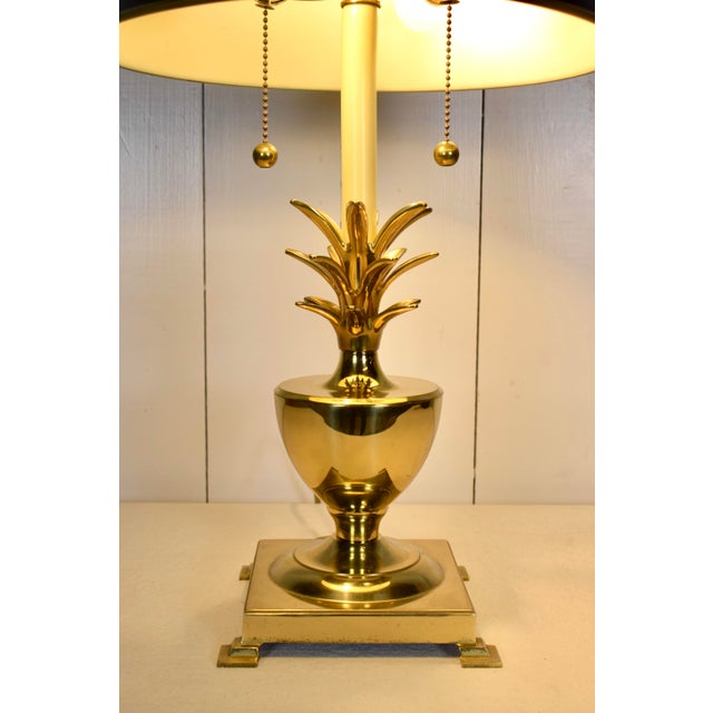 1970s brass pineapple lamp, in the style of Virginia Metalcrafters. The piece includes a black tole shade with gold piping...