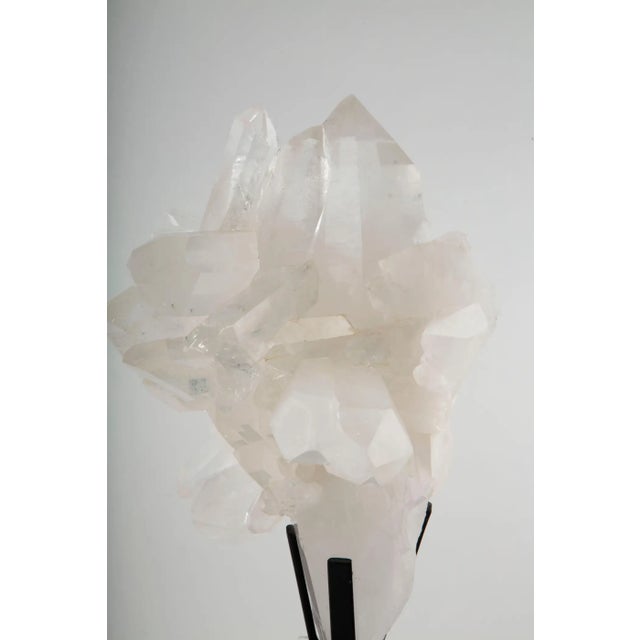 Large natural rock crystal (clear quartz) cluster, dramatically mounted on a custom black stand, featuring multiple well-...