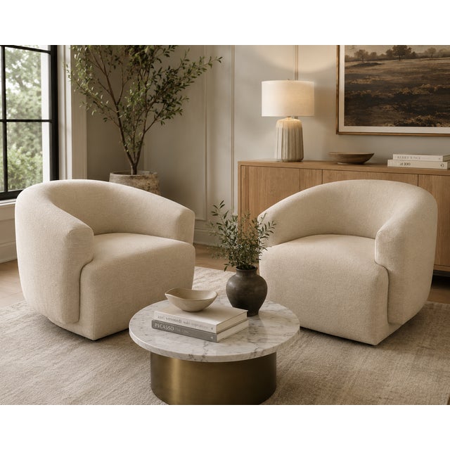 A sophisticated pair of contemporary swivel lounge chairs purchased from Arhaus, featuring sculptural curved silhouettes...