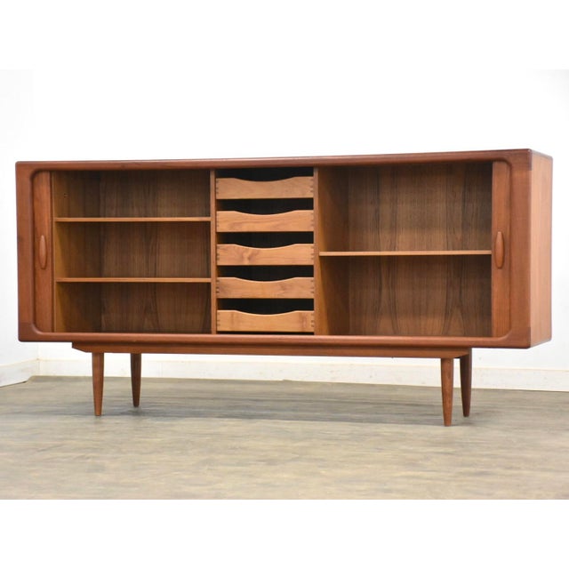 A mid century modern teak credenza with two sliding tambour doors made in Denmark by Dyrlund Furniture. Professionally...
