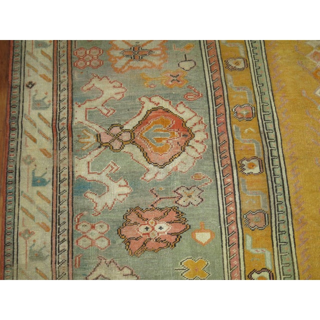 An early 20th century Turkish Ghiordes carpet with an all-over sunny yellow motif and green border. Measures: 12'6" x...