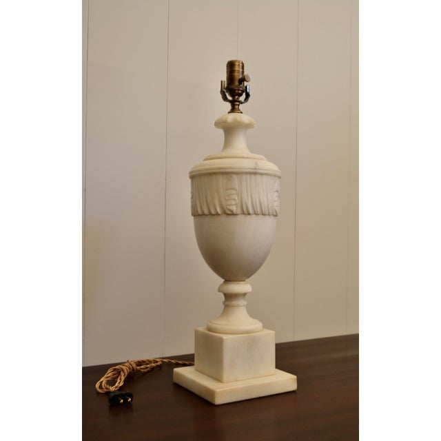 An exquisite early 20th century Neoclassical white marble lamp. The intricately carved urn silhouette is raised on a...