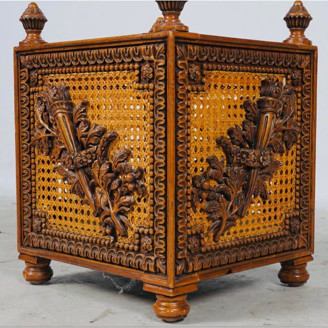 A richly carved 19th-century French jardinière featuring caned panels, classical torches, abundant foliage, and four...