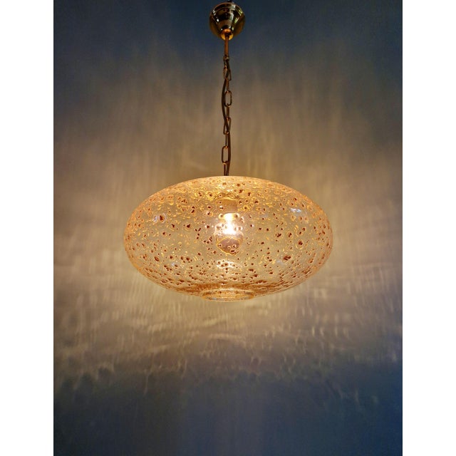 Large vintage pendant light in clear glass inlaid with gold glitter and a brass frame. Origin: Germany, 1970s. The pendant...