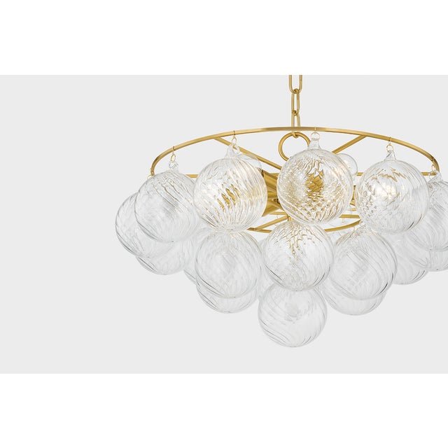 Swirl-ribbed or plated champagne glass globes dangle from an Aged Brass frame, creating this cloud-like showstopper....