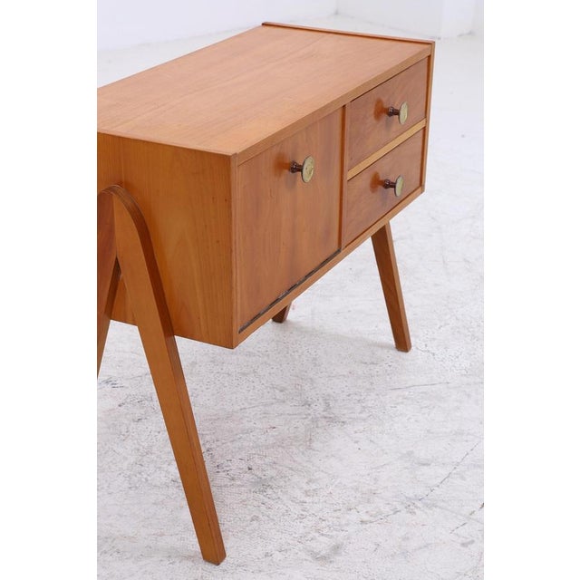 A beautiful vintage bedside table from the 60s with a clean, compact design and a calm, even grain. The drop-down door...