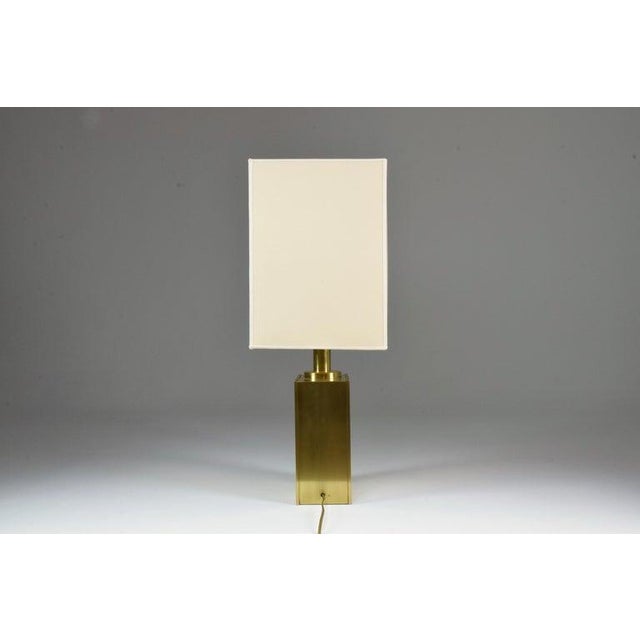 Italian table lamp from the 1970s with a rectangular, polished-brass body decorated with graphic engraved motifs. Its...