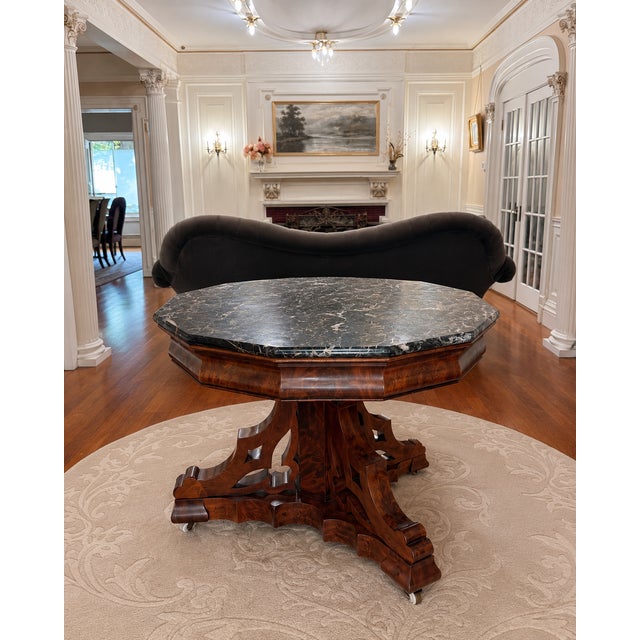 An elegant antique center table featuring a substantial octagonal black marble top resting upon an exceptionally well-...