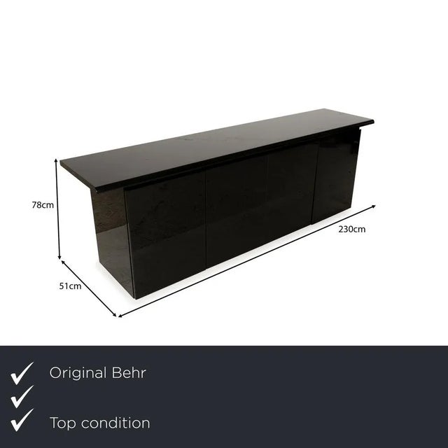 The Behr sideboard is crafted from black glass and wood and impresses with its classic design. The body rests on very low,...