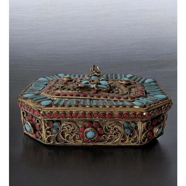 Tibetan or Nepalese filigree prayer box (Ghau) featuring a central deity figure on the hinged lid. The brass box is...