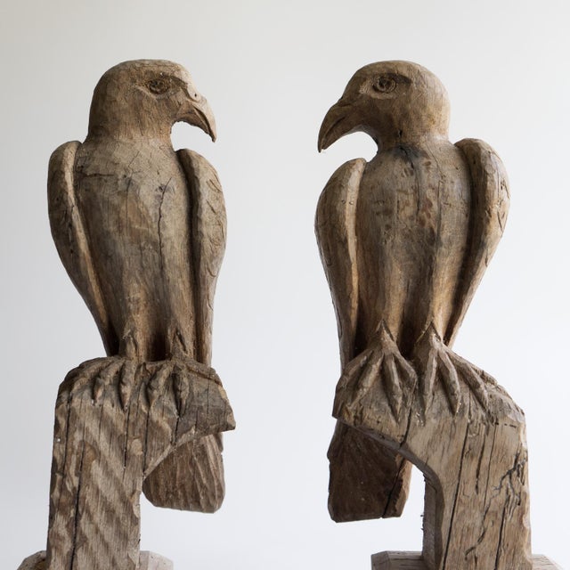 PAIR OF BIRD OF PREY CARVINGS Depicting a pair of birds of prey, believed to be falcons. Carved in a stylised naive folky...