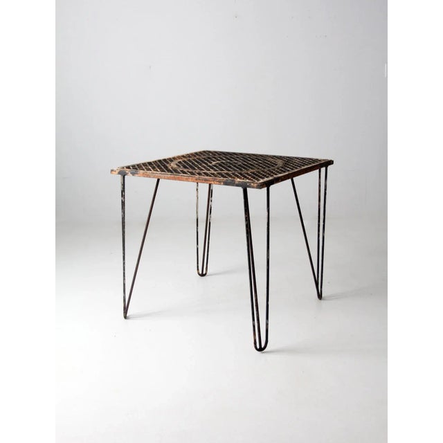 Mid-century iron patio table featuring a heavy, durable outdoor construction and a decorative iron gate-style top. The...