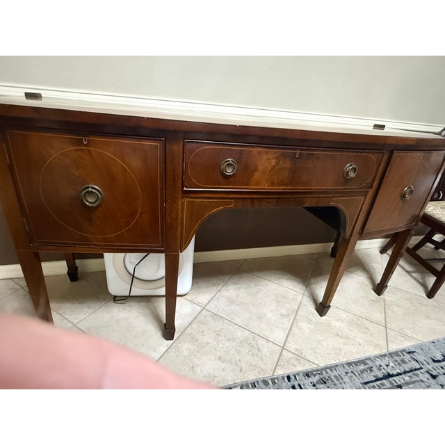 English George III mahogany sideboard ca.1780 plus later additions. The bow-front top with double stringing creates a...