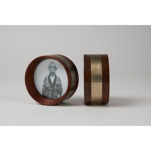 Double-sided circular photo frame in walnut wood with matte chrome-plated brass joints and protective glass. Manufactured...