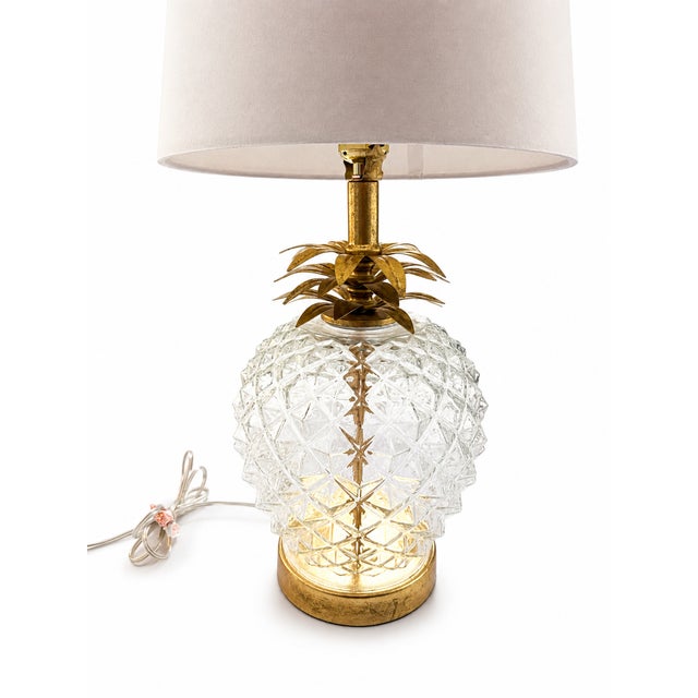 A charming pineapple-form table lamp featuring a substantial faceted clear glass body with layered antiqued gilt-metal...