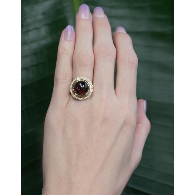 A bold 10.6 Ct Rubellite Tourmaline center stone (10mm) radiates deep raspberry-red color, surrounded by a sparkling...