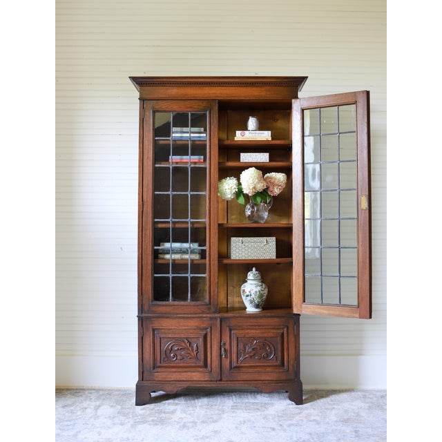 Crafted in the early 20th century from English oak, this handsome leaded glass bookcase features a rich, time-worn patina...