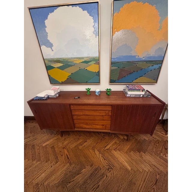 Classic Scandinavian credenza in teak, roughly 6 feet long. Two sliding doors with hand-carved oval finger pulls open to...