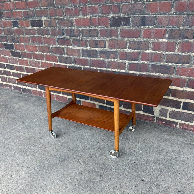 An authentic Danish Modern drop-leaf tea trolley designed by Hans J. Wegner for Andreas Tuck and made in Denmark. This...