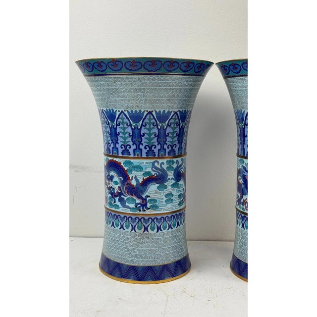 Pair of large Chinese cloisonne trumpet-form vases featuring imperial blue dragon design amid cloud scrolls and geometric...