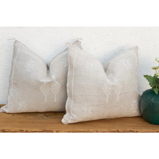 Sold as a matching pair, these handcrafted Moroccan cactus silk pillows feature a stylized four-legged figure motif at...