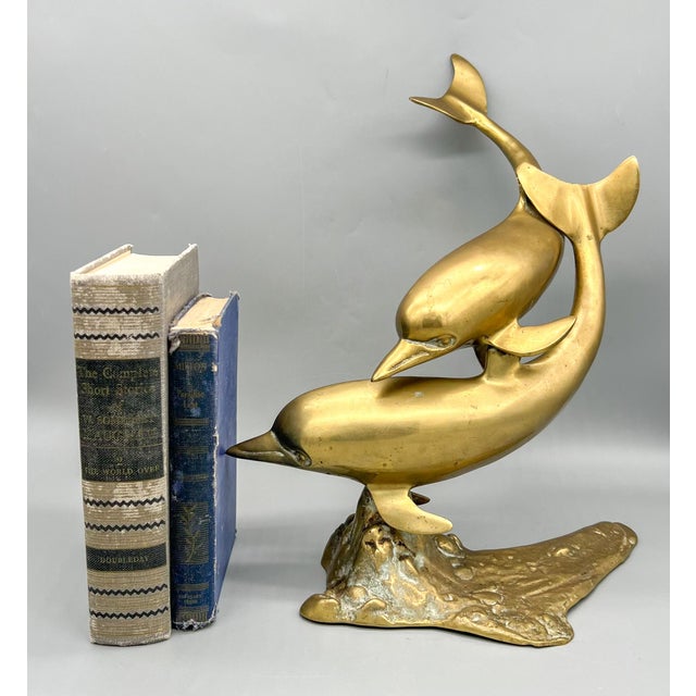 Charming and bright double dolphin figure made of brass. Mid-late 20th century Hollywood Regency piece. Features two...