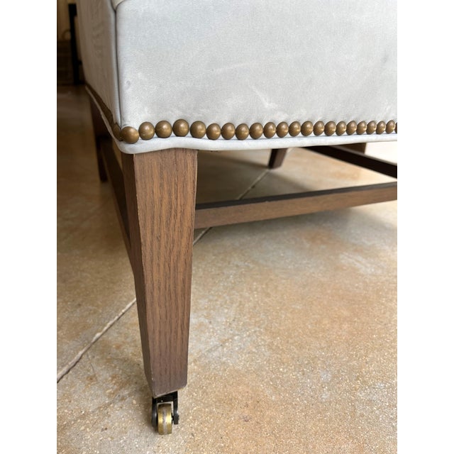 Blue suede club chair with brass nail-head trim, loose back cushion, tapered wood legs, and front casters. Features soft...