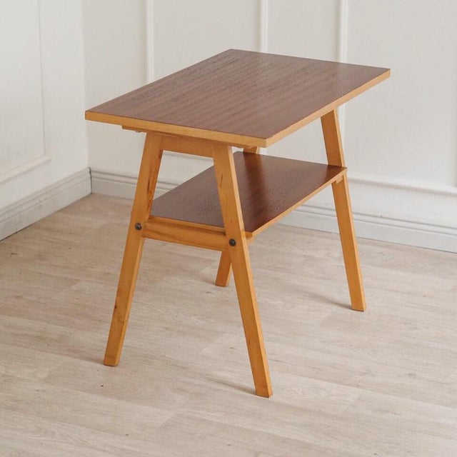 A two-tiered side table, made in Germany in the 1960s, originating from the Dresden area. The angled, tapered legs and the...