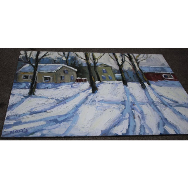 Winter light stretches from a quiet snowscape of buildings, trees casting long shadows and creating a sense of depth and...