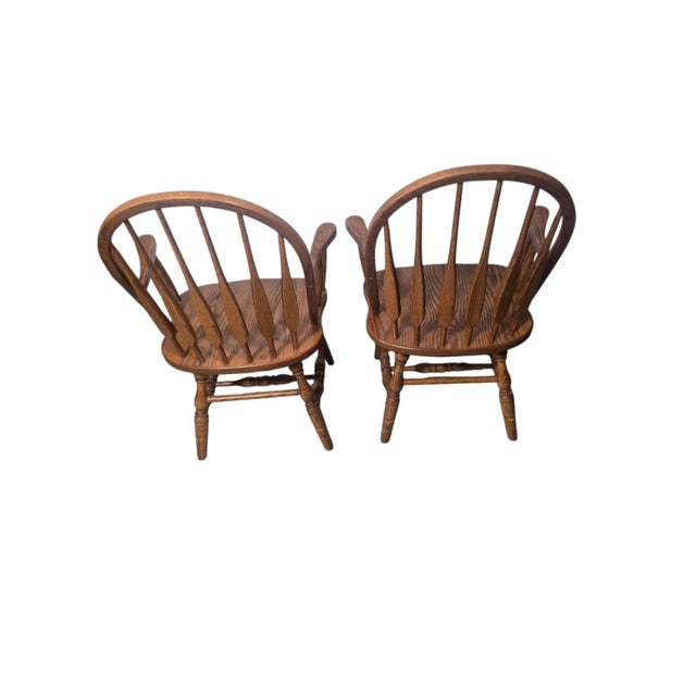 A handsome pair of vintage Windsor-style armchairs featuring gracefully curved bow backs, elongated paddle-form spindles,...