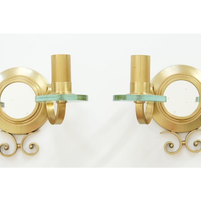 Exceptional pair of French wall sconces dating from circa 1940, finely crafted in gilt bronze and glass, each centred by a...