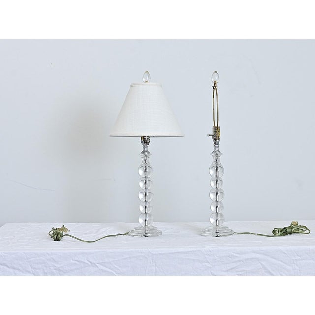 French, vintage pair of table lamps made of solid, clear glass spheres stacked in a column. Below an egg-shape finial of...