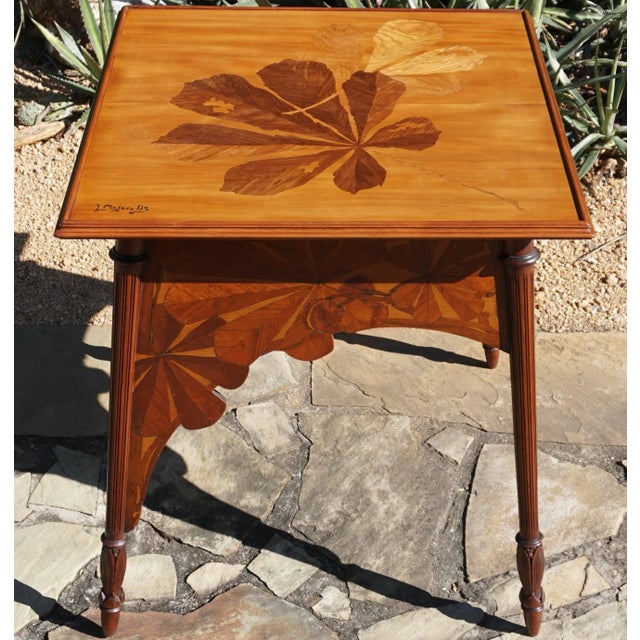 A French Art Nouveau marquetry walnut and exotic wood game table signed by Louis Majorelle. The tabletop is decorated with...